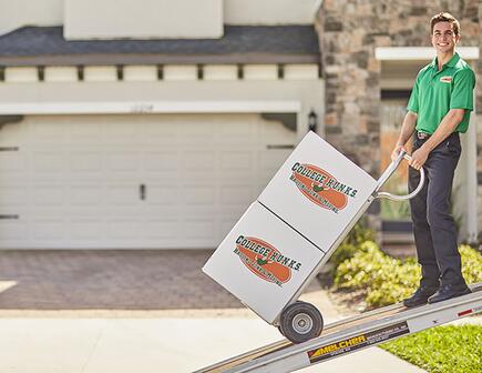 college hunks mover using dolly to transport moving boxes