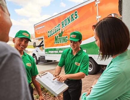 Two College HUNKS movers talking to a family