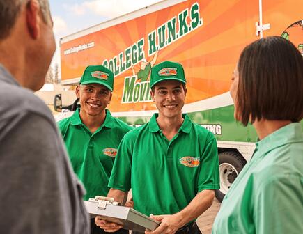 Two College HUNKS movers talking to a family